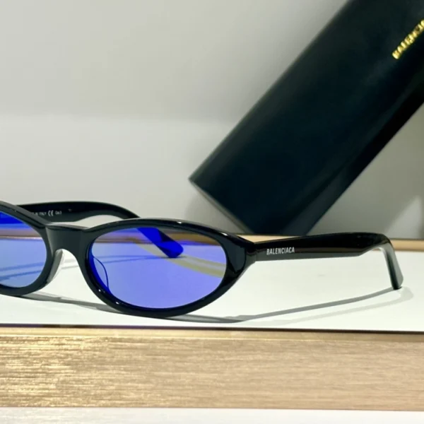 Balenciaga Neo round sunglasses resting on white surface with smooth curves and embossed branding
