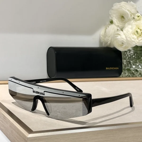 Balenciaga Ski sunglasses laid flat on white surface with curved rectangular frame and sleek arms