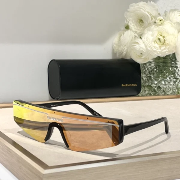 Flat lay of Balenciaga Ski rectangle sunglasses alongside branded case and accessories