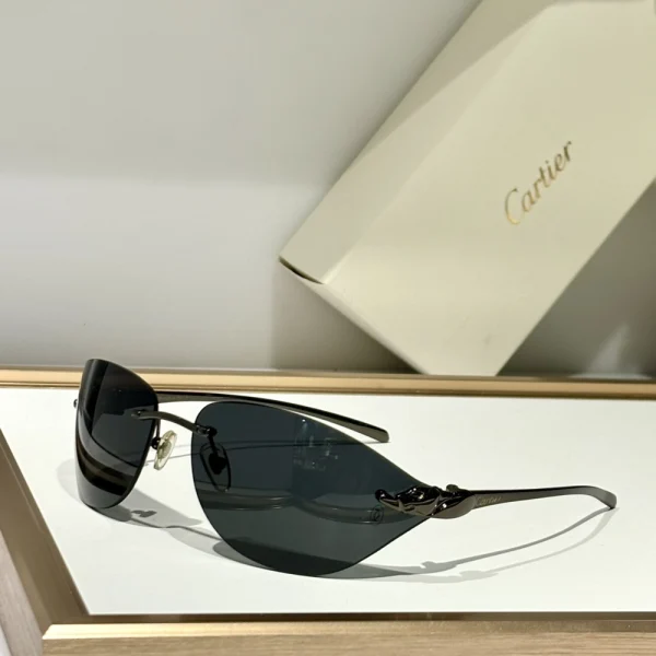Close-up of Cartier Panthère de Cartier sunglasses on white marble, showcasing shimmering gold panther embellishment