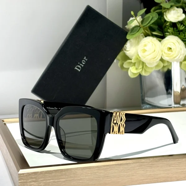 Black Dior MissDior S2F sunglasses placed diagonally on marble surface under soft natural daylight