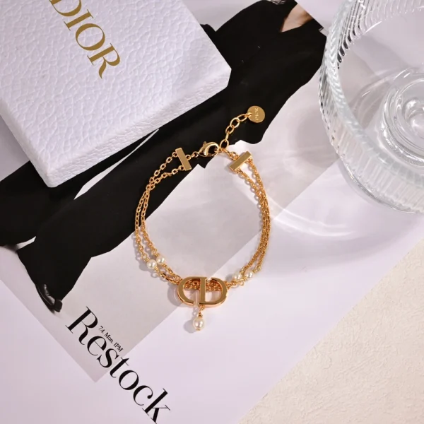 Close-up of Dior gold Petit CD bracelet featuring minimalist design