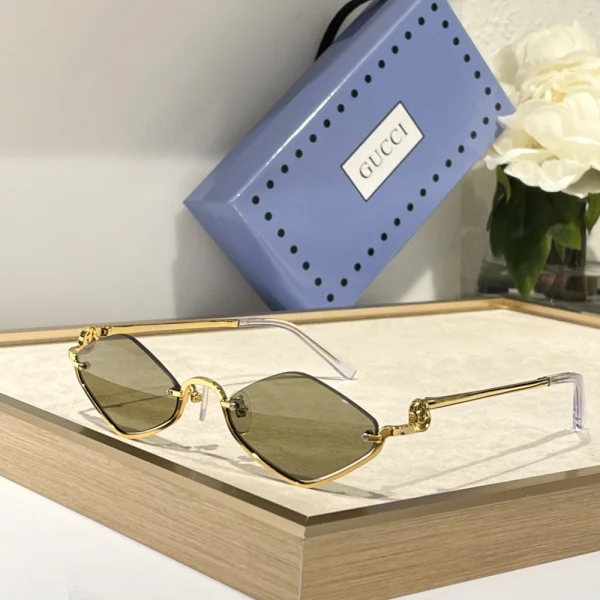 Gucci geometric sunglasses resting on a white surface with branded packaging in the background