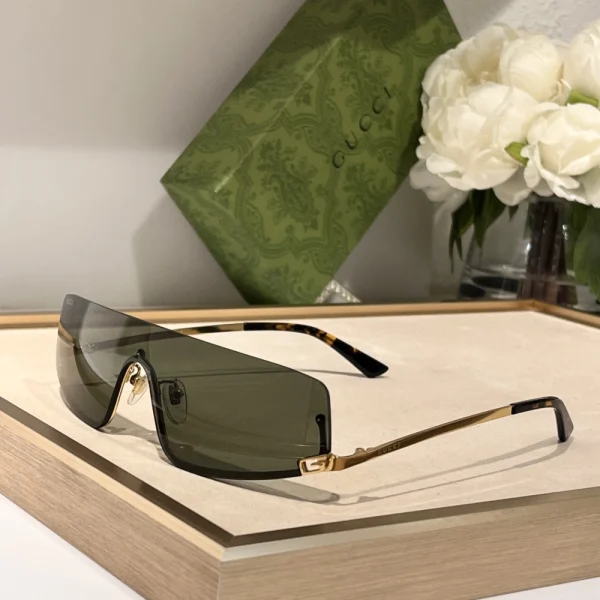 Gucci mask sunglasses placed on white surface with case and accessories in background