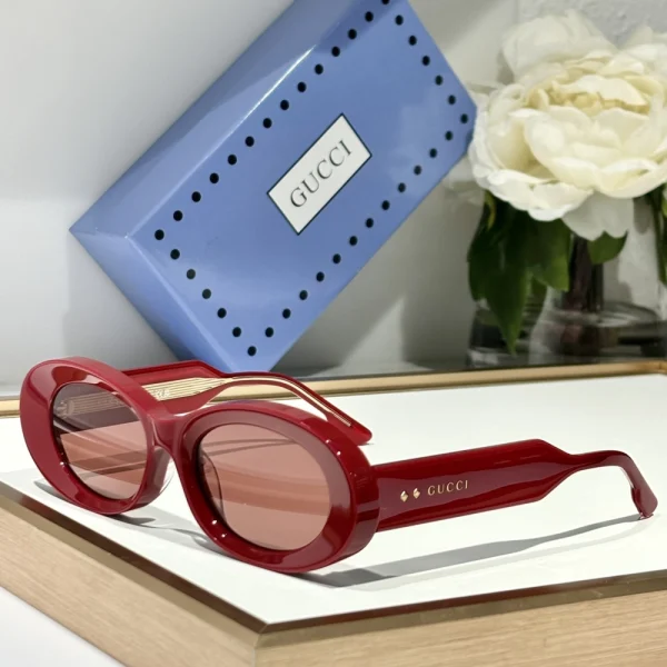 Gucci designer sunglasses in oval shape, photographed on white surface with branded case