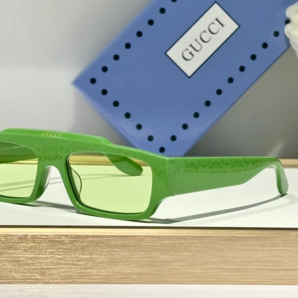 Gucci rectangular-frame sunglasses positioned diagonally on matte background for editorial effect