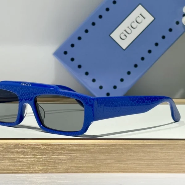 Gucci rectangular-frame sunglasses laid neatly on white surface, highlighting slim temples and precision-cut lenses