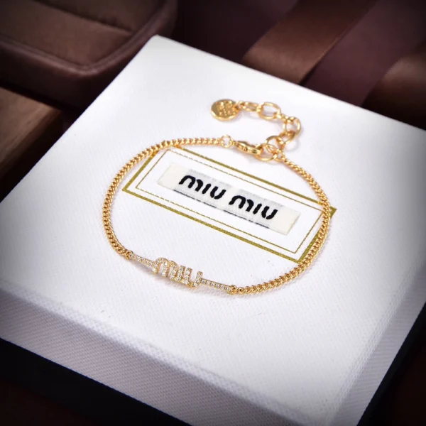 Miu Miu gold charm bracelet featuring polished finish and signature decorative pendants