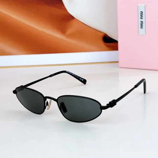 Model wearing Miu Miu oval sunglasses with sleek black frame and visible logo, styled for a casual chic look