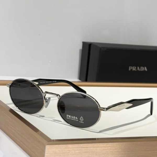 Prada Eyewear Collection sunglasses with bold black acetate frame and dark lenses, displayed on minimalist white surface