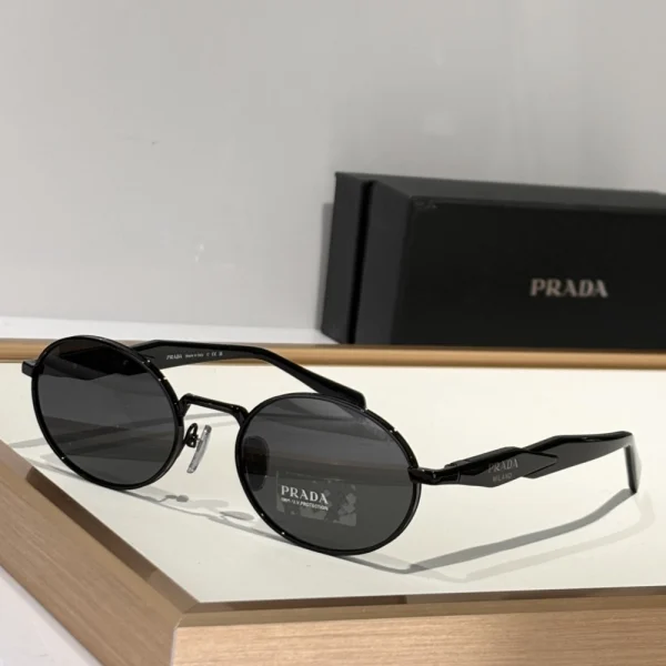 Black Prada sunglasses from the Eyewear Collection resting beside original case and branded cleaning cloth