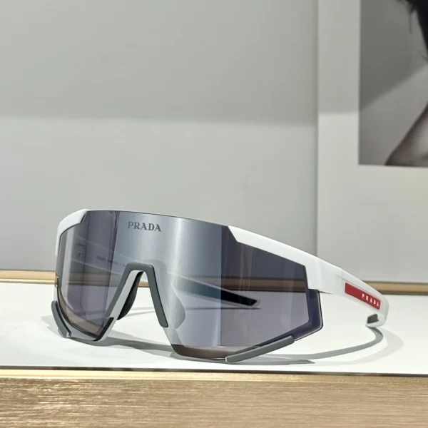 Front view of Prada Linea Rossa Impavid sunglasses with seamless shield lens, styled with branded case and cloth