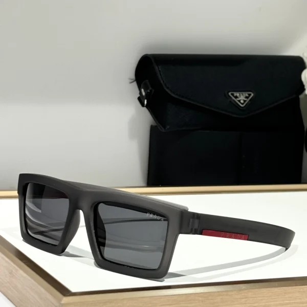 Prada Linea Rossa Impavid sunglasses placed diagonally on a white desk, emphasizing curved shield lens and futuristic silhouette