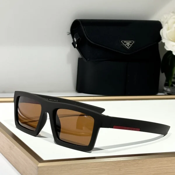 Prada Linea Rossa Impavid sunglasses in glossy black finish, resting beside a water bottle and smartwatch for sporty vibe