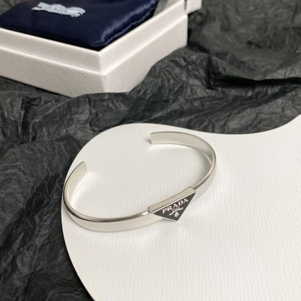 Prada logo bracelet featuring iconic triangle emblem and sleek modern design in polished metal.