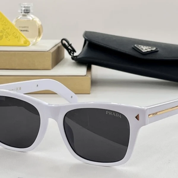Close-up of Prada sunglasses showing the signature metal Prada plaque embedded into glossy acetate temples