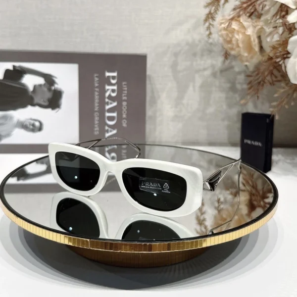 Close-up of Prada sunglasses highlighting the iconic metal triangle logo embedded on the side of the frame