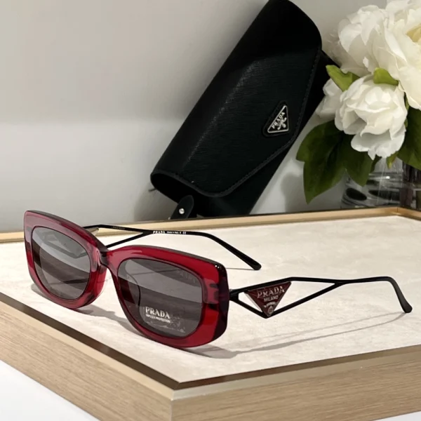 Triangle-logo Prada sunglasses placed on a white surface, showcasing minimalist design and luxury branding