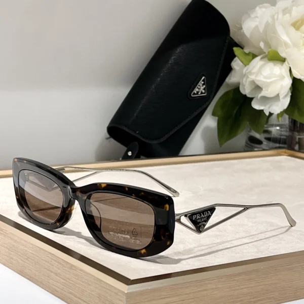 Prada triangle logo sunglasses in tortoiseshell finish, laid flat with soft natural lighting