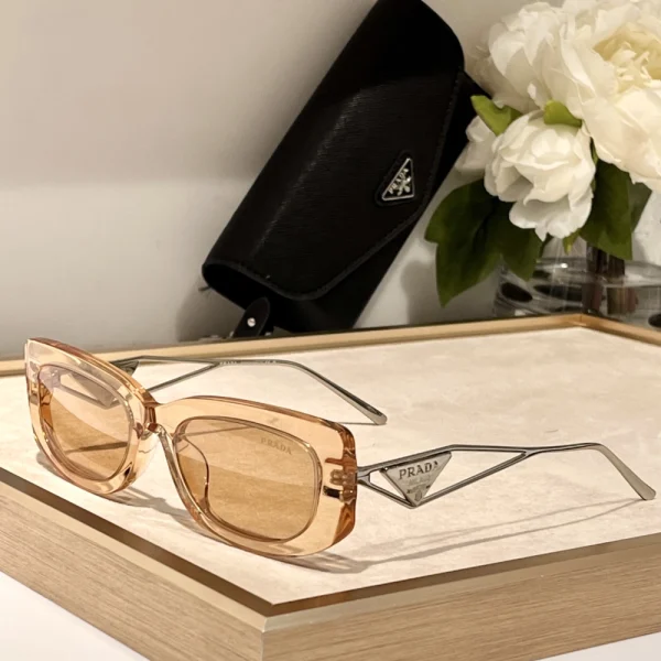 Detail shot of Prada triangle logo accent on glossy black sunglasses, capturing refined Italian craftsmanship