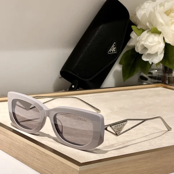 Side view of Prada sunglasses with triangular logo plaque, emphasizing bold temples and fashion-forward silhouette
