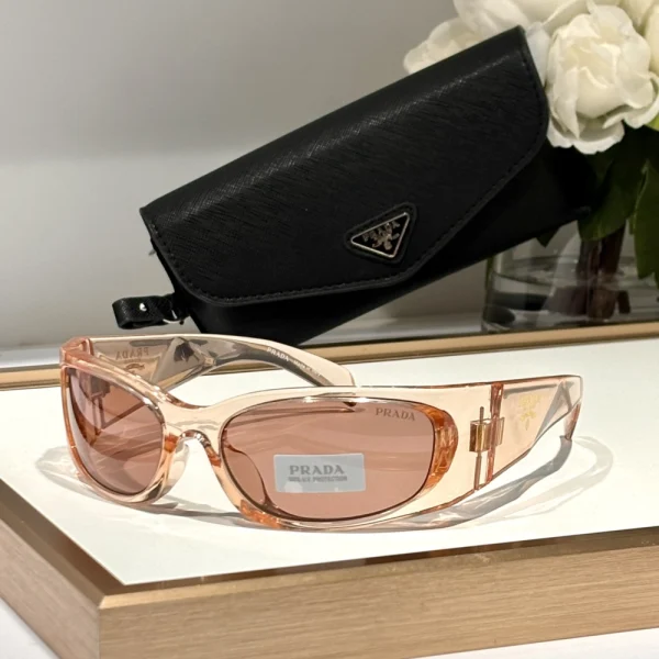 Side angle of Prada Symbole sunglasses with chunky arms and raised Prada emblem, placed next to branded box