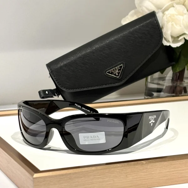Black Prada Symbole sunglasses with gradient lenses and triangle logo, styled on minimal white table