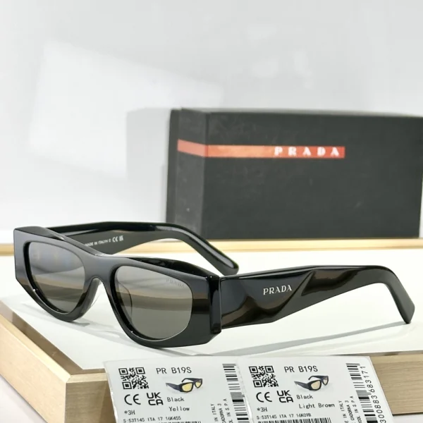 Black Prada Symbole sunglasses resting beside original case, highlighting luxury design and branding