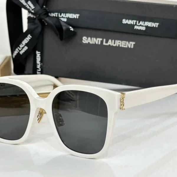 Elegant Saint Laurent Monogram SL M40 sunglasses resting on a white tabletop beside branded eyewear case