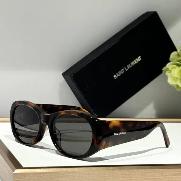 Modern Saint Laurent SL 736 sunglasses styled on white tabletop, paired with the original branded box