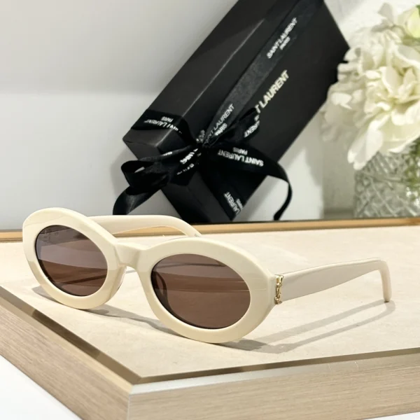 Saint Laurent SL M136 sunglasses with sleek rectangular black frame and dark grey lenses, styled on a white tabletop