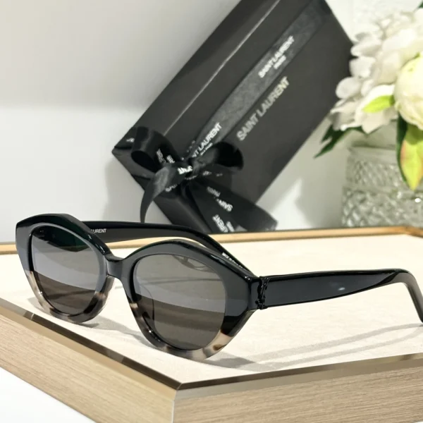 Elegant SL M148/F sunglasses by Saint Laurent resting on a white tabletop with branded case in the background