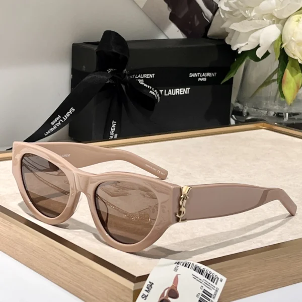 Saint Laurent SL M94 sunglasses featuring bold square black frame with dark grey lenses, styled on a white tabletop
