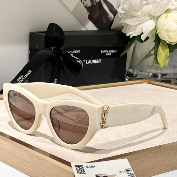 Luxury Saint Laurent SL M94 sunglasses with dark gradient lenses, styled on beige fabric background