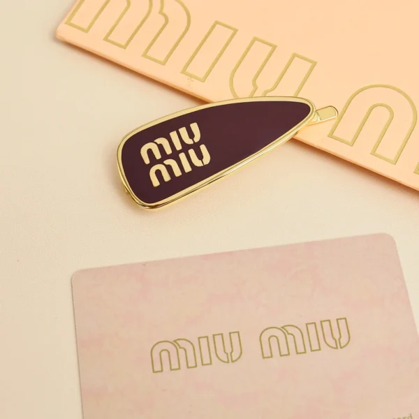 Miu Miu enameled hair clip placed on textured fabric for style display
